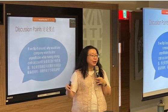 Dr Jenny Tan speaking with a microphone in front of her discussion-points slides
