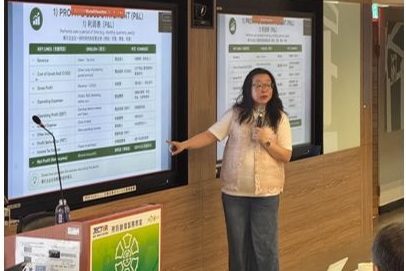 Dr Jenny Tan pointing to a profit-and-loss slide during the lecture